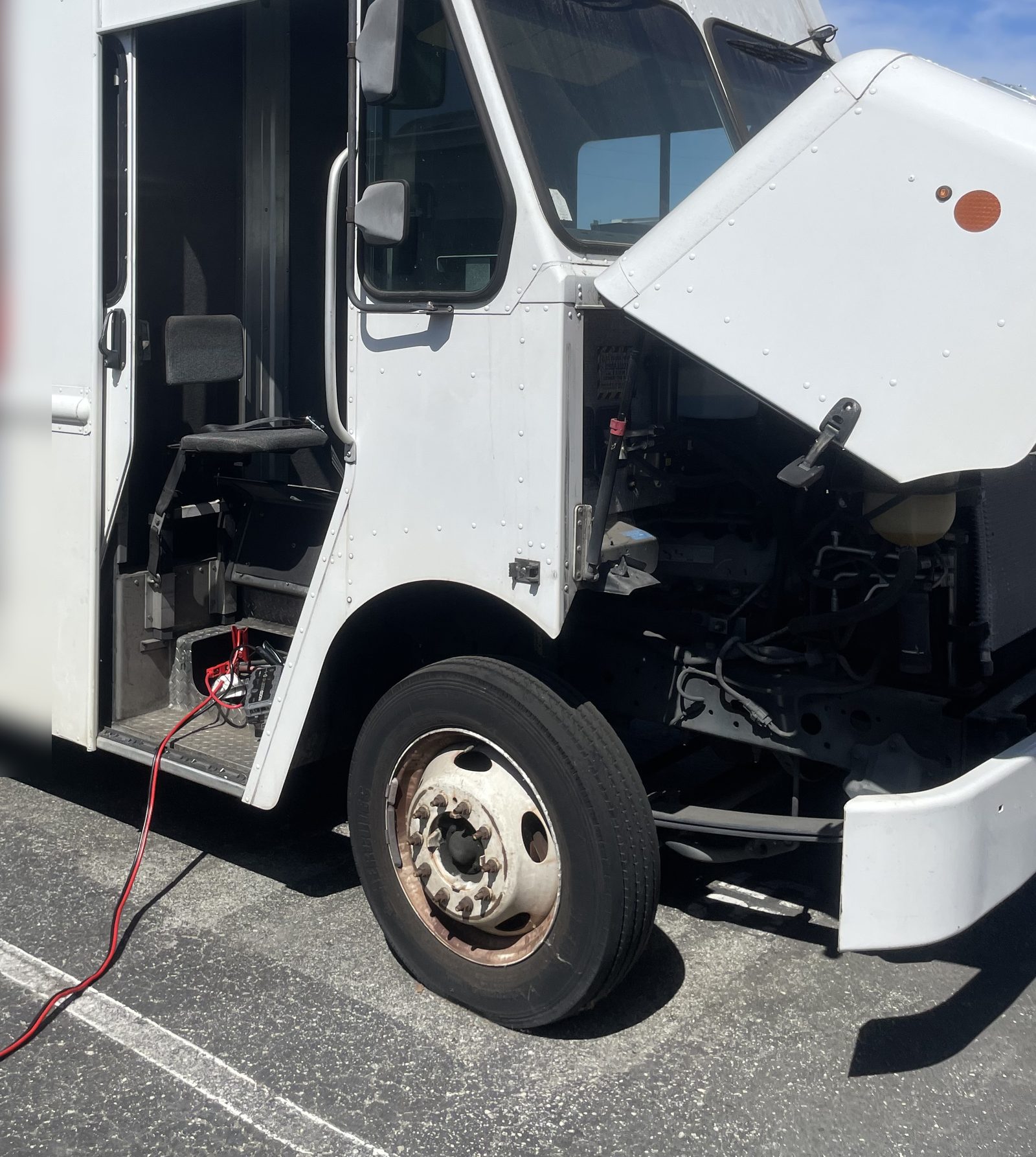 Axl Roadside jump start on a commercial delivery truck: hood open with jumper cables connected