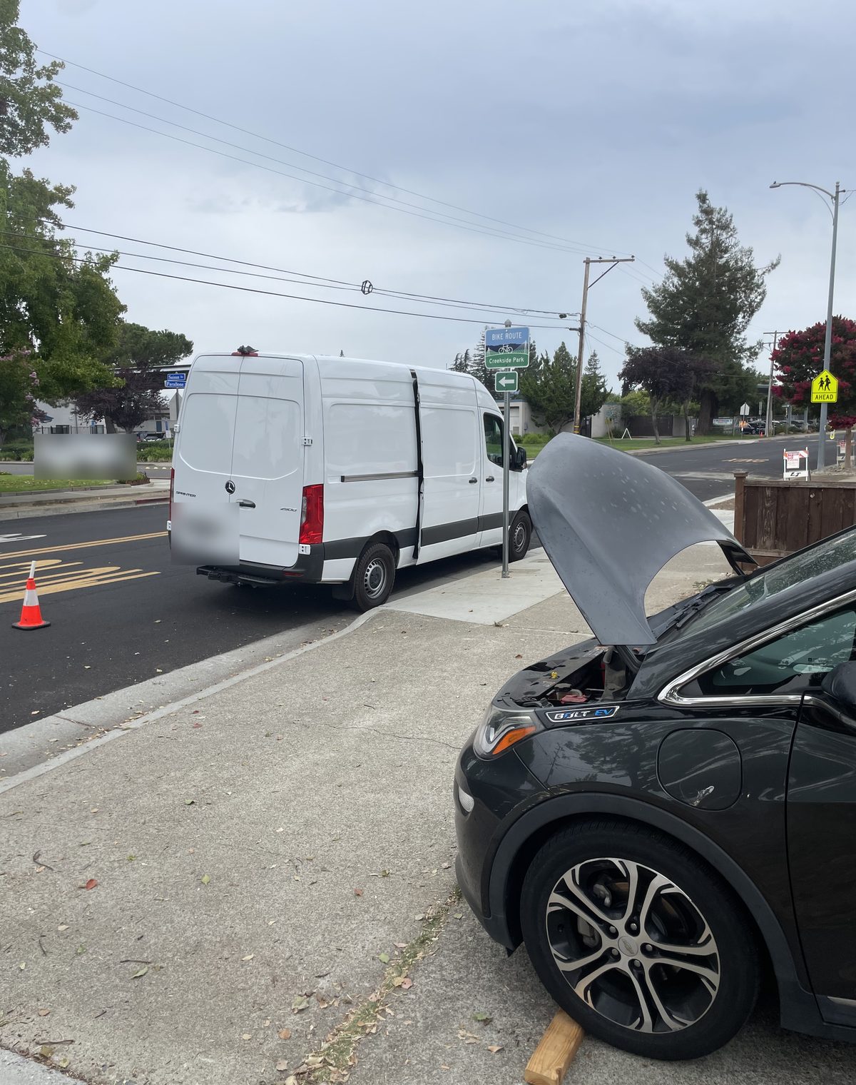 Axl Roadside helping a Chevrolet Bolt EV at the curb with the hood open