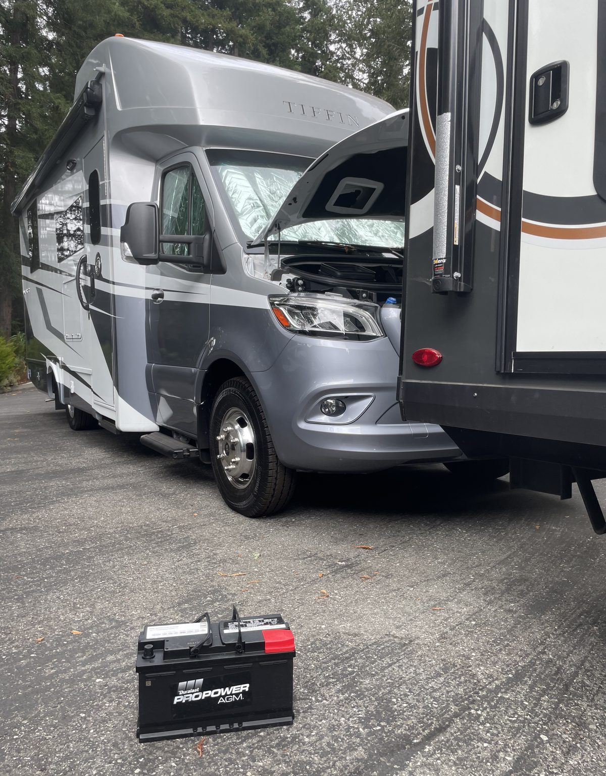 Axl Roadside battery replacement on a motorhome: hood open with the new AGM battery ready on the ground