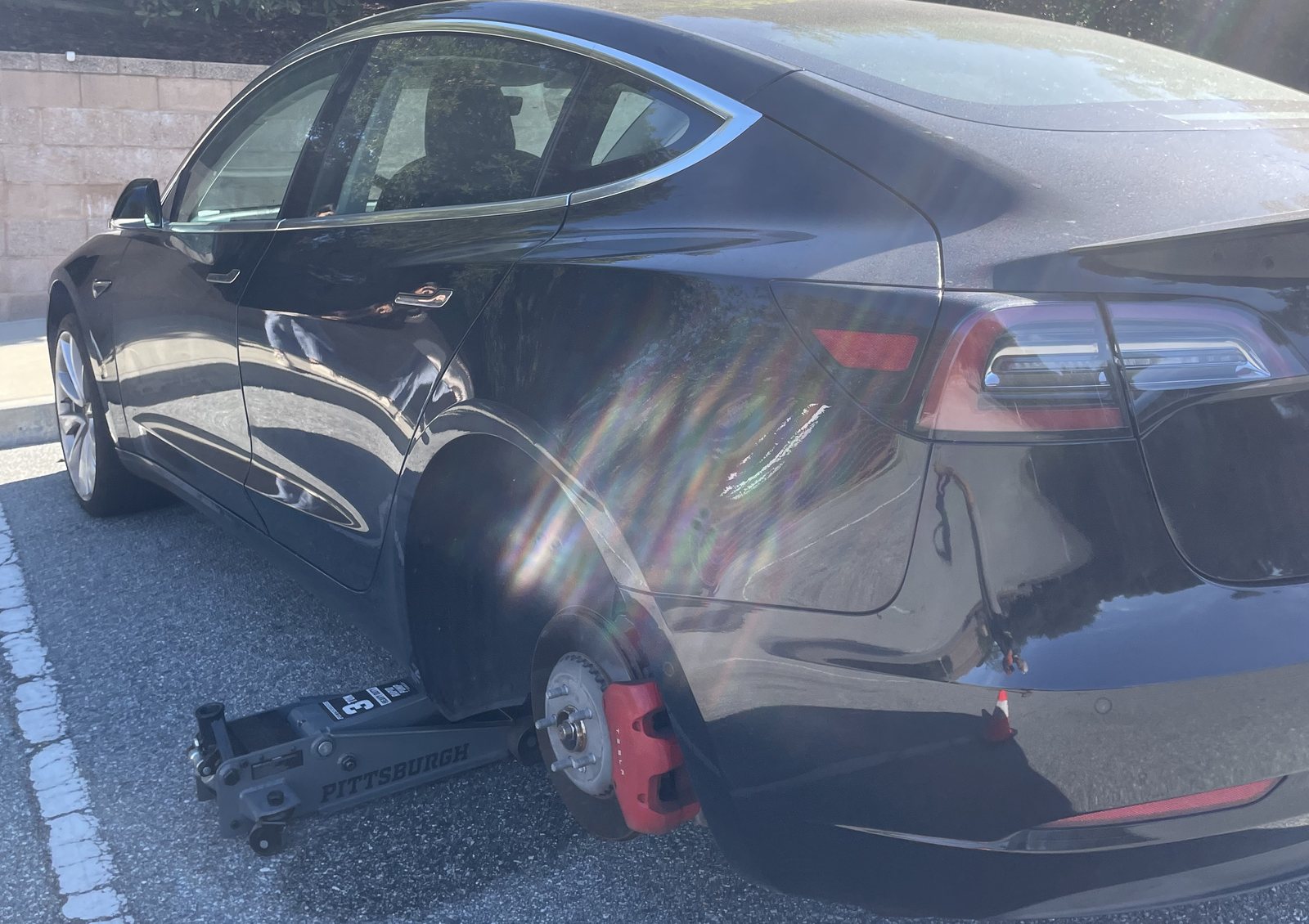Axl Roadside flat tire job on a Tesla in a parking lot with the rear wheel off