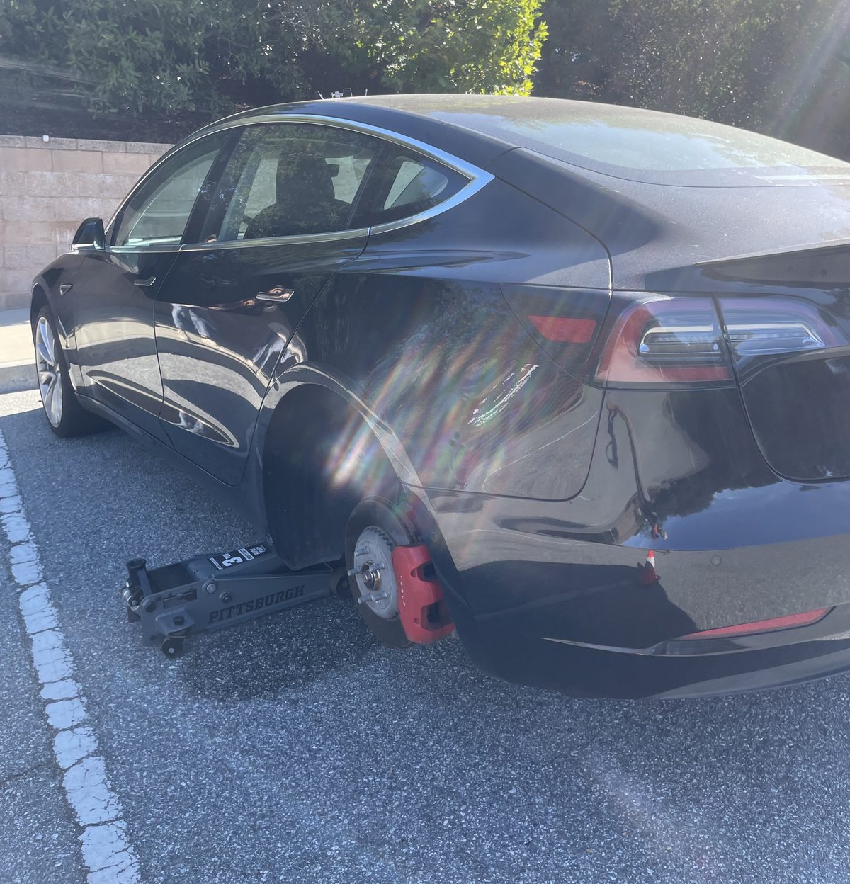 Axl Roadside flat tire job on a Tesla: wheel off and the car on a floor jack in a parking lot